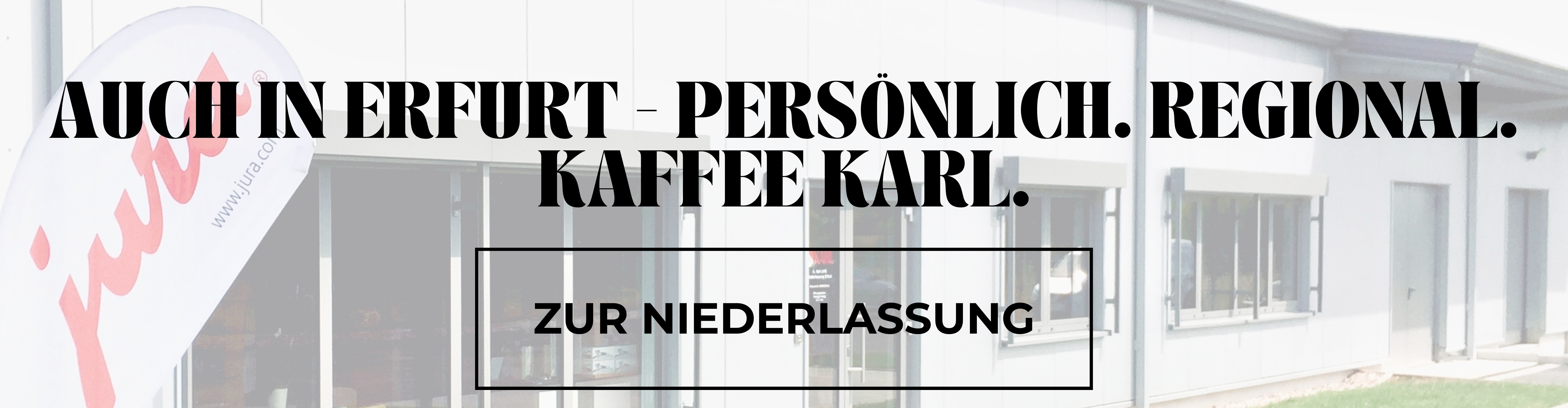 Außenansicht der Kaffee Karl Niederlassung in Erfurt-Kerspleben mit Beachflag und rotem JURA-Schriftzug vor einem grauen, länglichen Firmengebäude